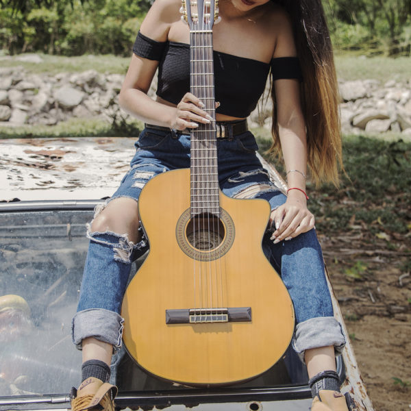 seated girl holding Washburn classical guitar outside