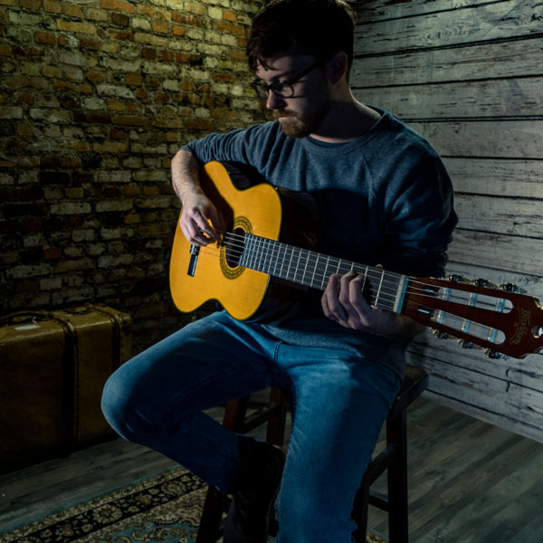 man playing Washburn acoustic guitar