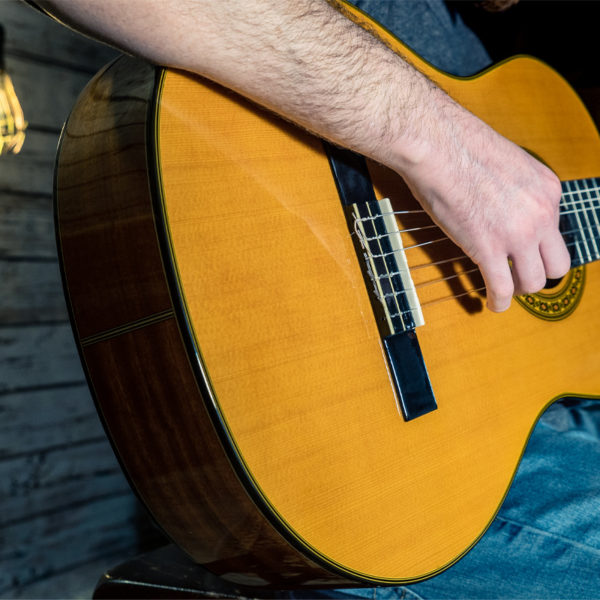 partial view of man playing Washburn acoustic guitar