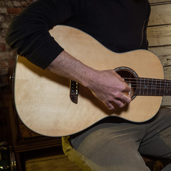 partial view of man playing Washburn acoustic guitar