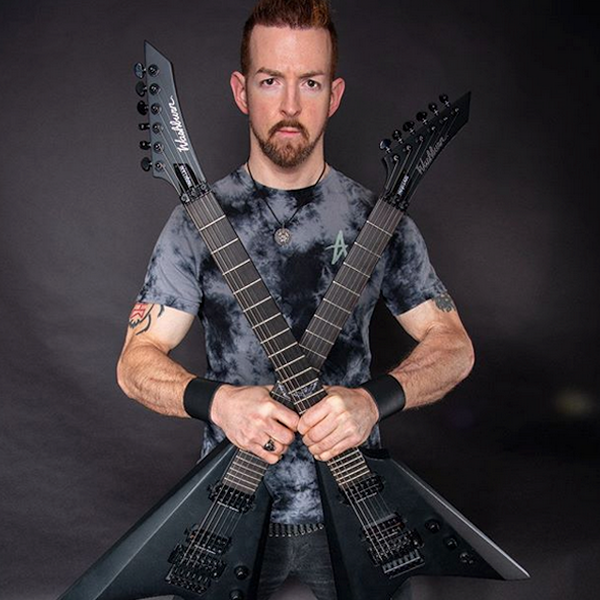 male musician holding two black Washburn electric guitars