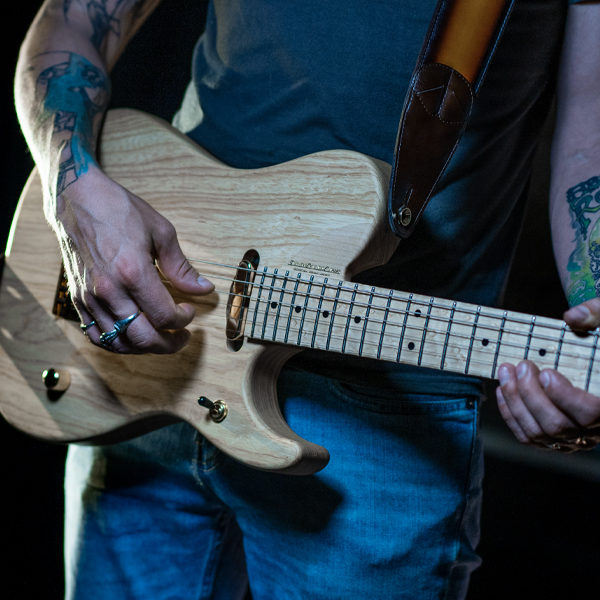 partial view of man playing Washburn electric guitar