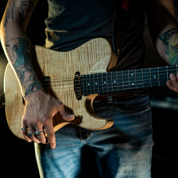 partial view of man playing Washburn electric guitar in concert